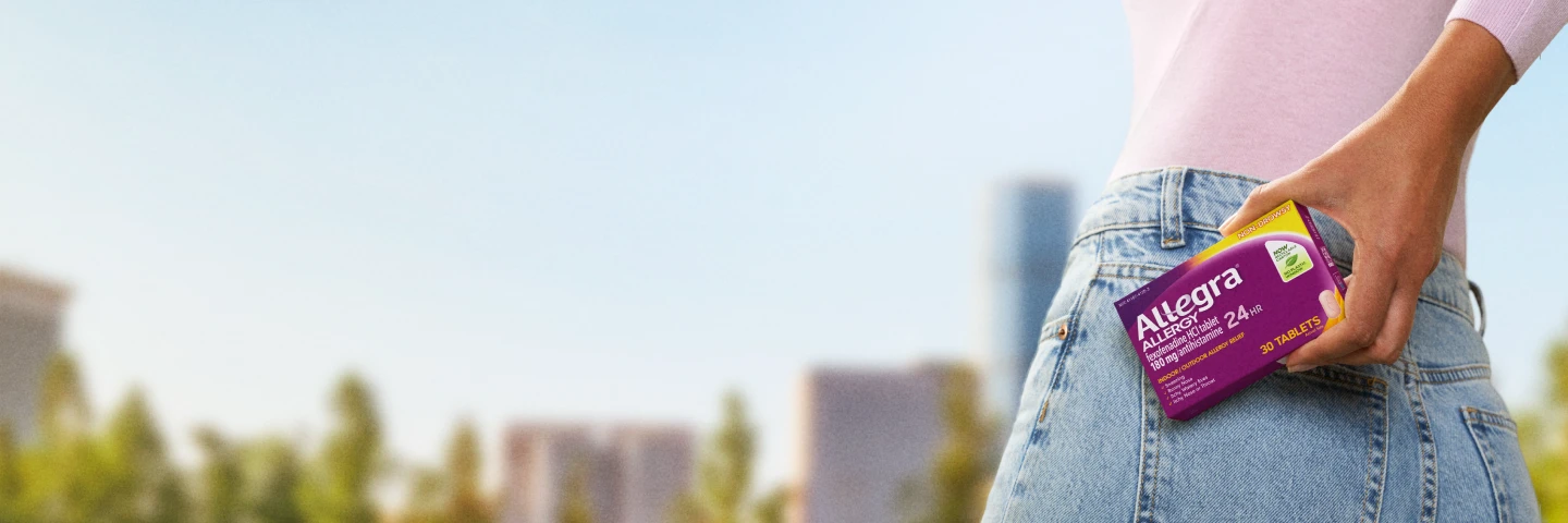 Woman holding a box of Allegra 24 hours allergy relief in urban setting